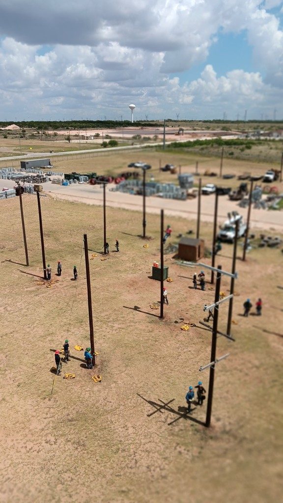 A bird's eye view of poles with a student on one pole and the rest working on the ground.