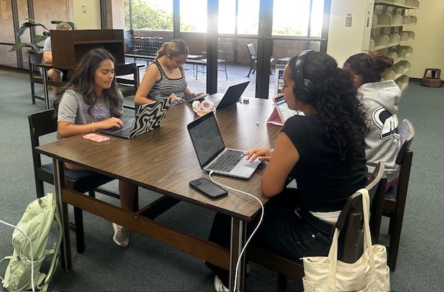 Four students study at a table in the Library.