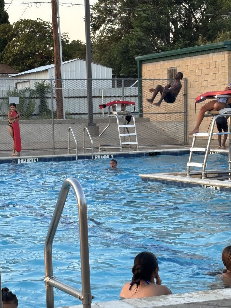 A student does a cannonball off the diving board.