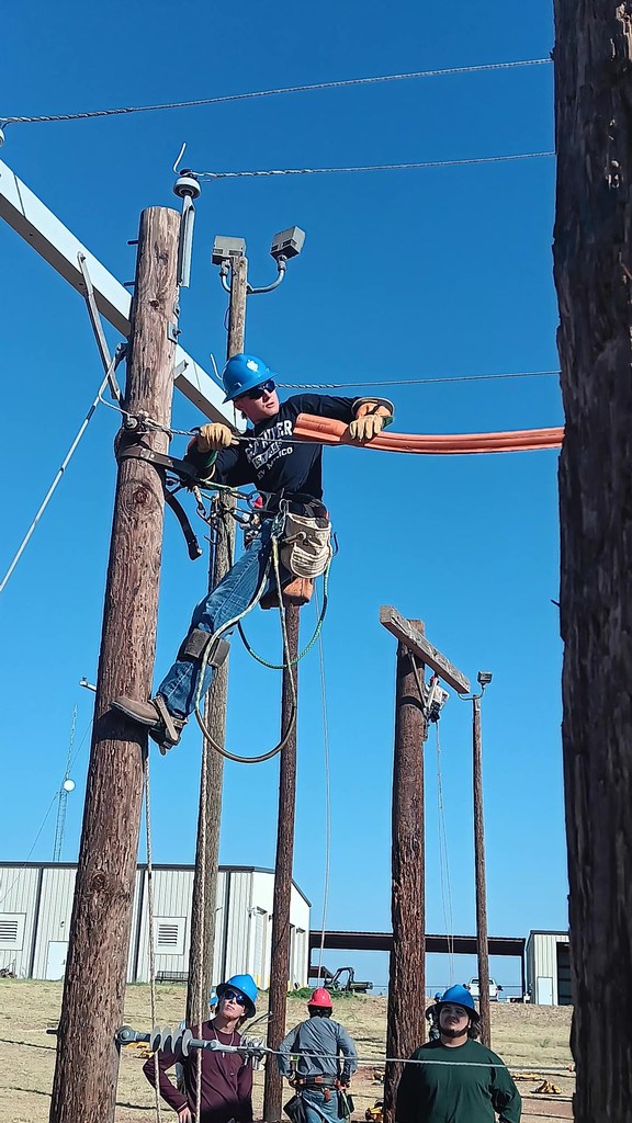 A student on a pole installs rubber hose.