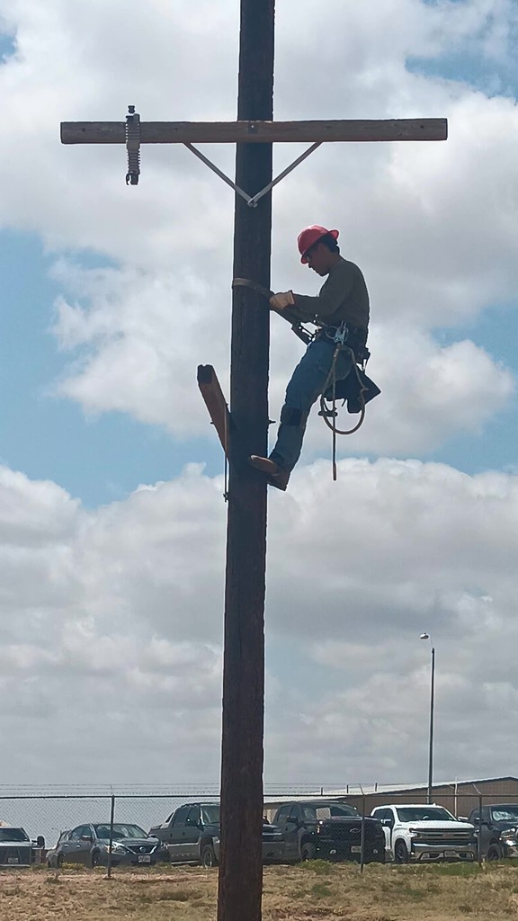 A student climbs a pole to perform a crossarm changeout.