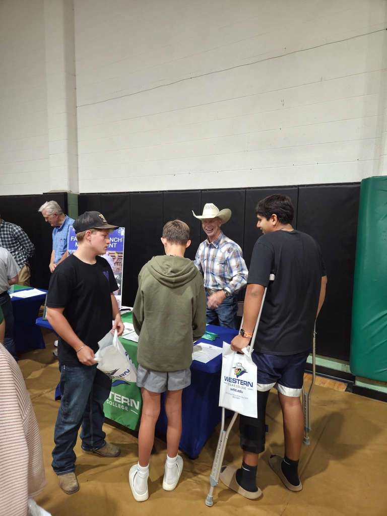Jay Waller speaks with three students at a booth during the college fair.