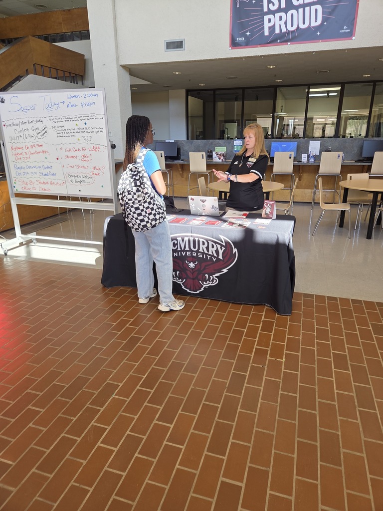 A McMurry University recruiter speaks to a student at a table in the student center.
