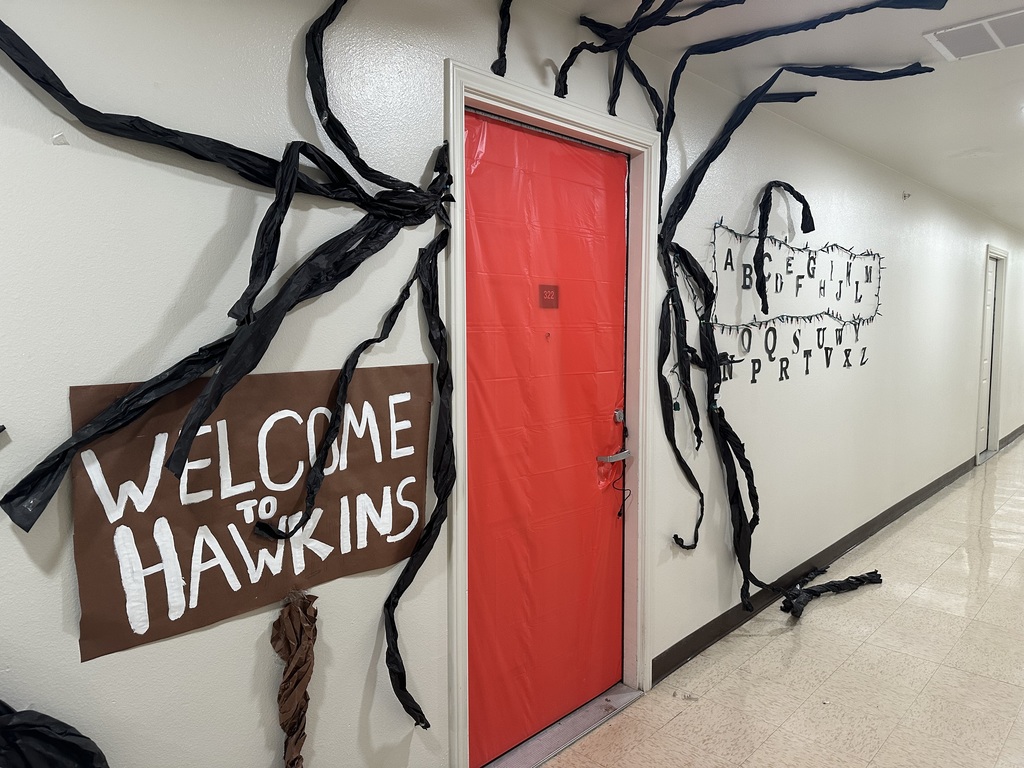 A red door with scary branches and a sign that reads, "Welcome to Hawkins."