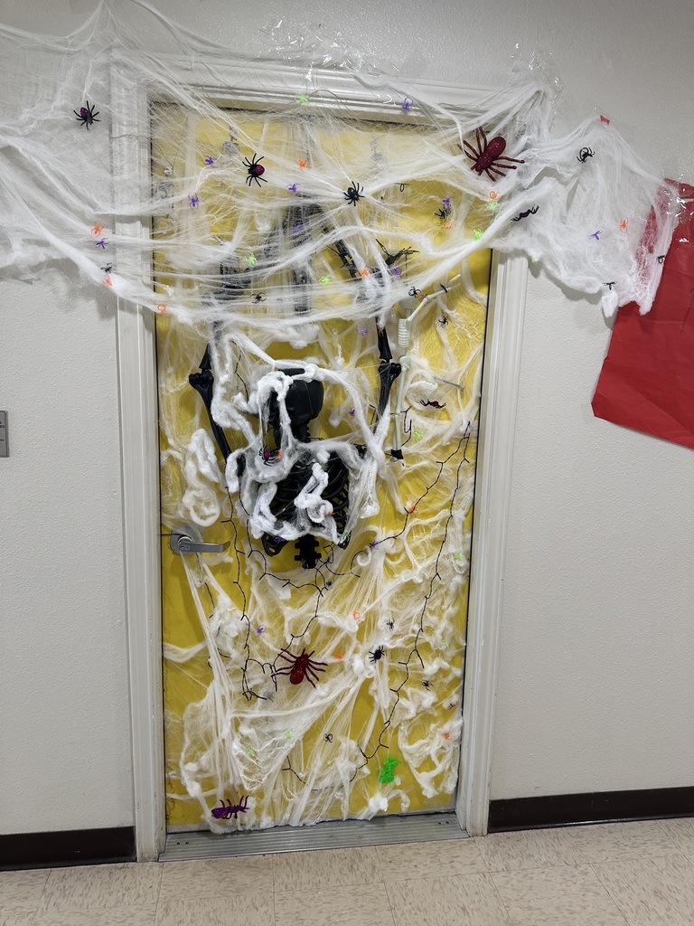A dorm door decorated for Halloween with spider webs and a yellow background.
