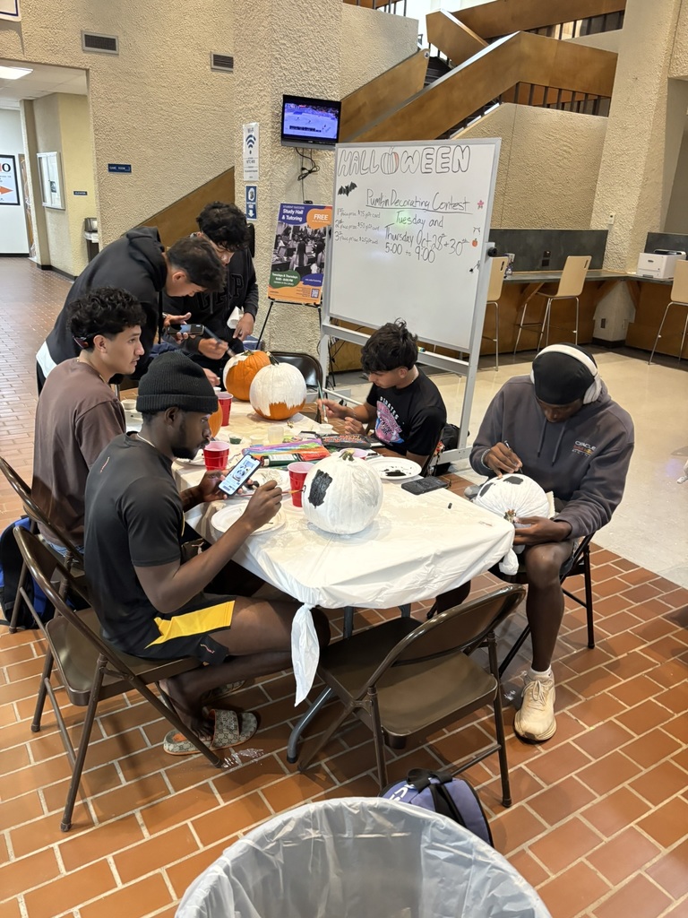 Group of students seated around a table painting pumpkins for the contest.