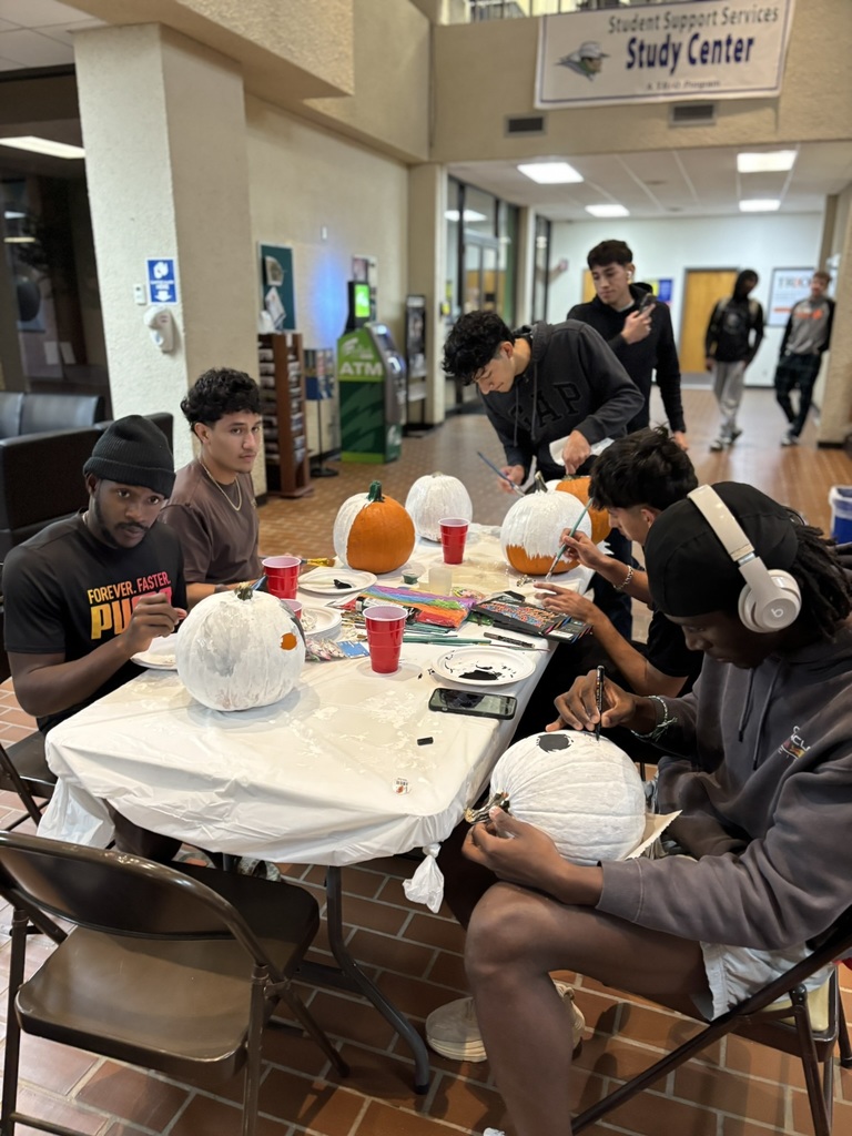 Group of students focused on painting pumpkins at a table in the Student Center.