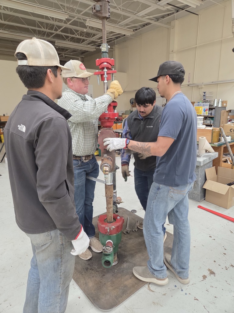 Students work together assembling oilfield equipment during a hands-on training session in the classroom workshop.