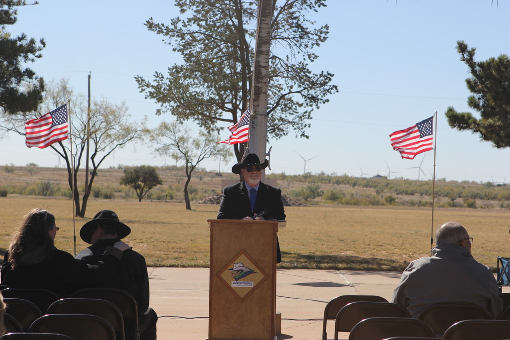 Dr. Scates stands at podium with American flags during WTC Veterans Day Ceremony.