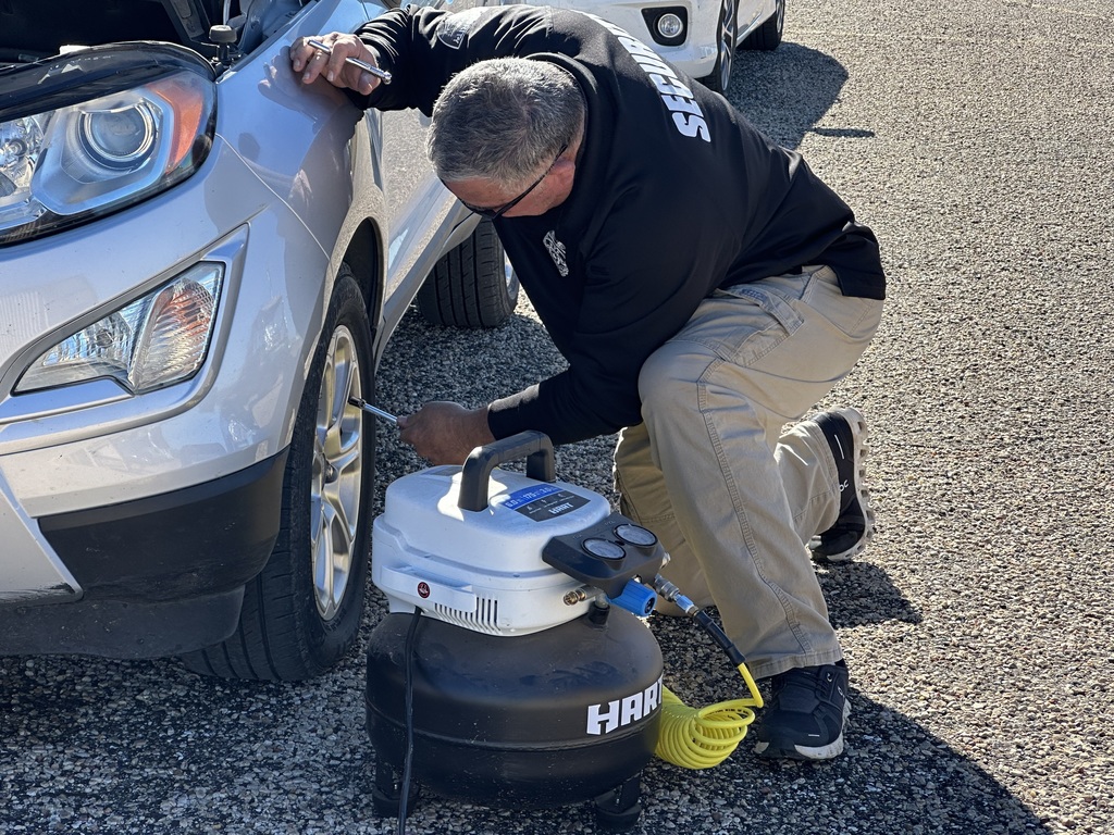 Jamie Redwine checks the tire pressure on a student's vehicle.