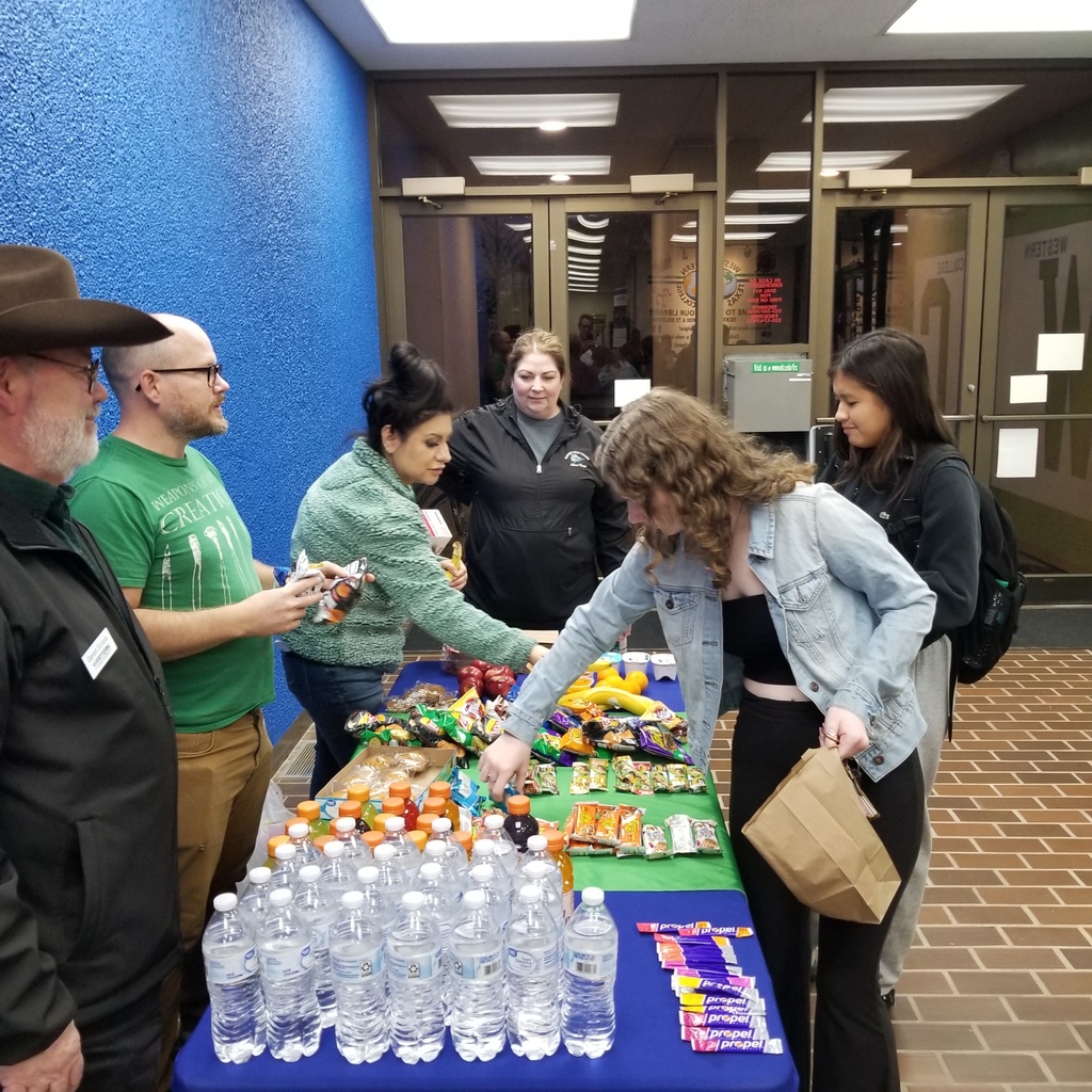 Students fill to-go bags with snacks, helped by faculty members in the Library foyer.