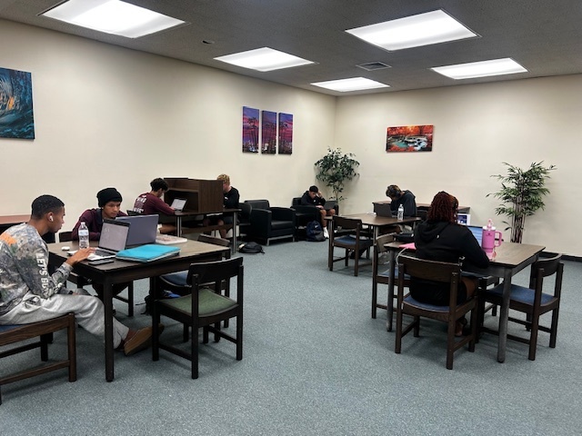 Students sit at tables studying upstairs in the Library.