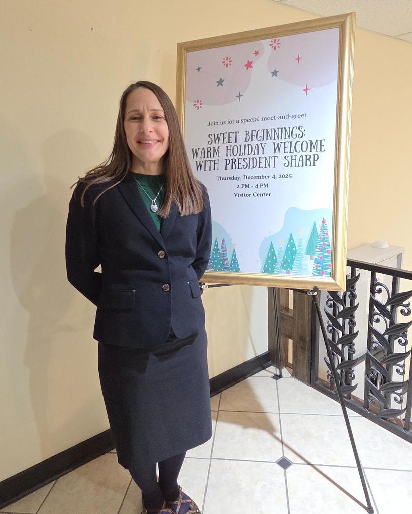 Dr. Sharp smiles next to a poster for the event.
