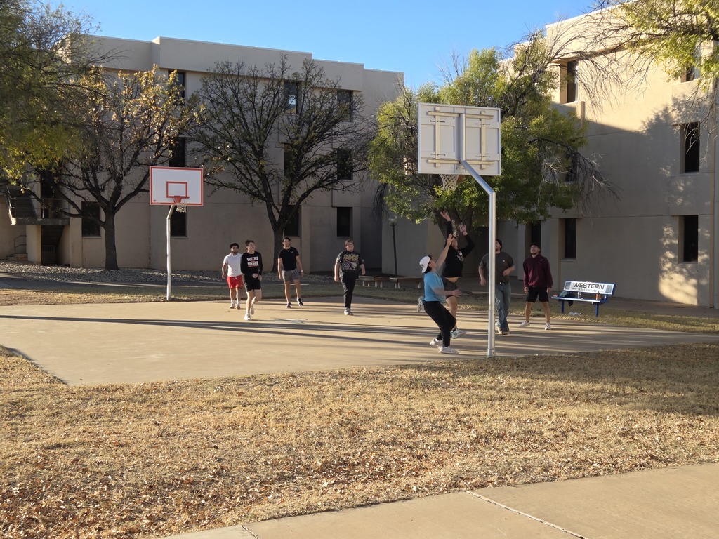 Students play a pickup game of basketball on the court in front of West Hall.