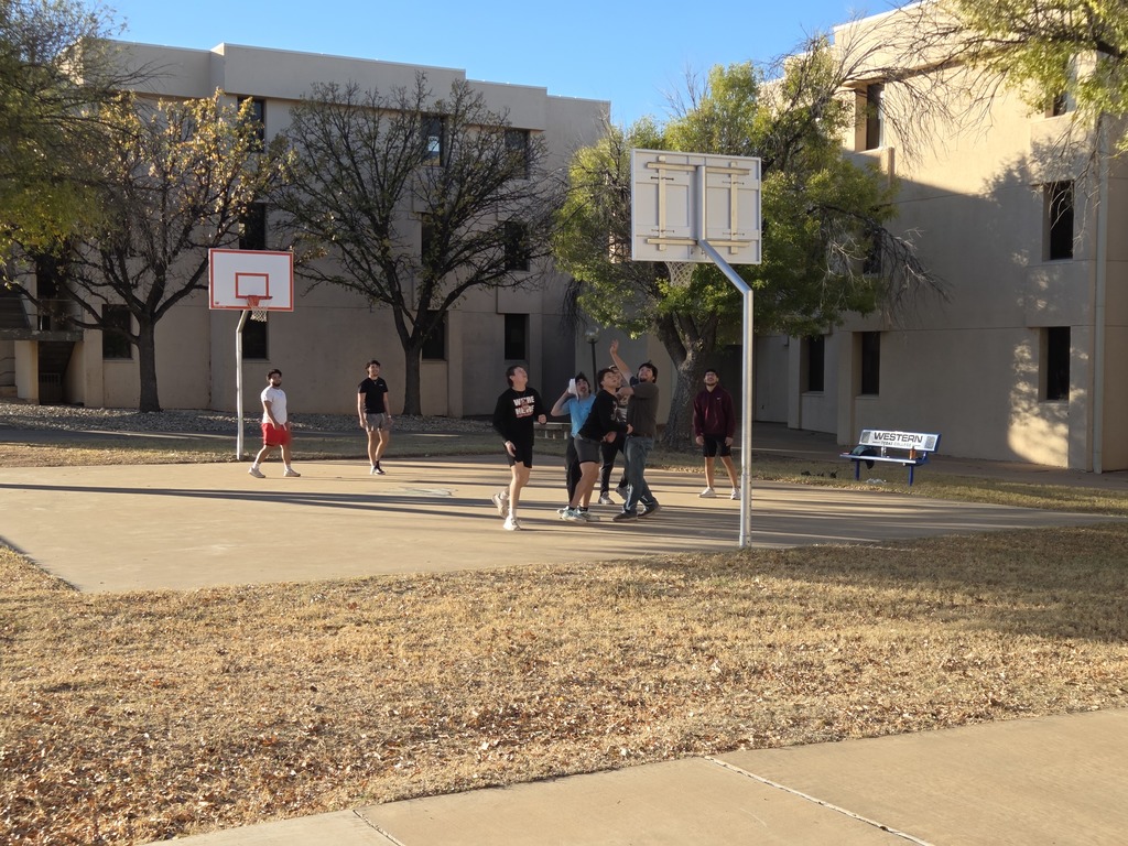 Students play a pickup game of basketball on the court in front of West Hall.