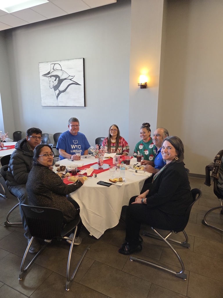 Faculty and Staff seated at a round table with holiday decorations.