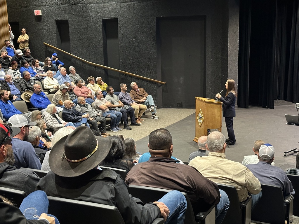 Dr. Sharp stands on the stage speaking to employees in the audience.