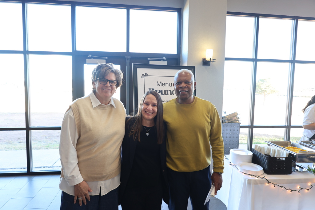Dr. Sharp, Tammy and Darryl Davis smile in front of the windows in the cafeteria.