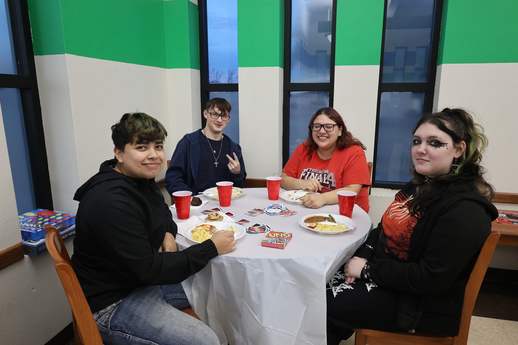 Students sitting at a table and smiling while having BBQ.