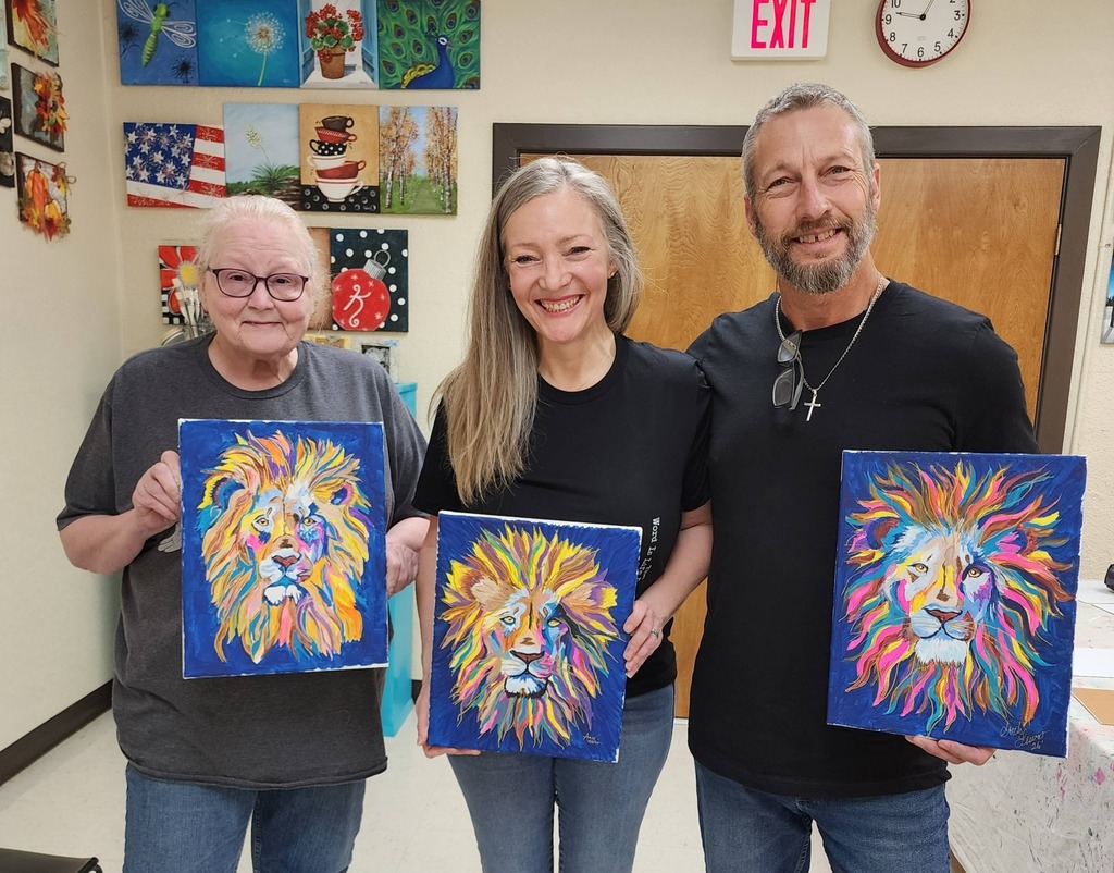 People holding paintings of colorful lion