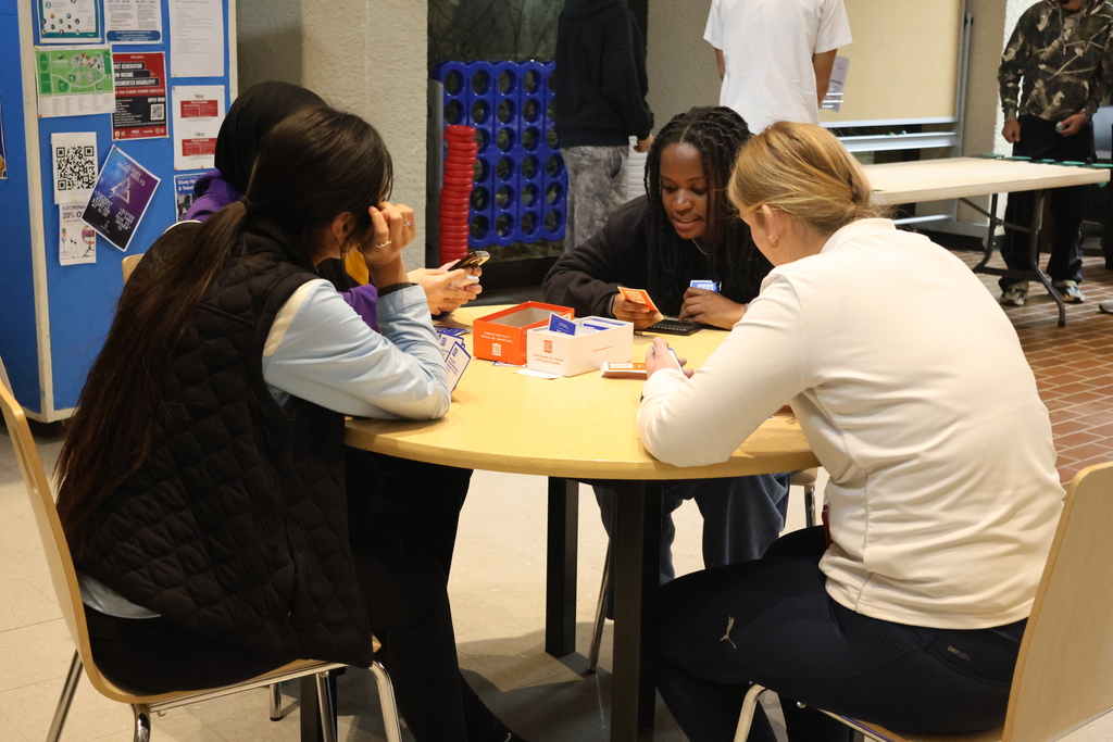Students lean over a table, focused on a card game at WTC Student Center Game Night.