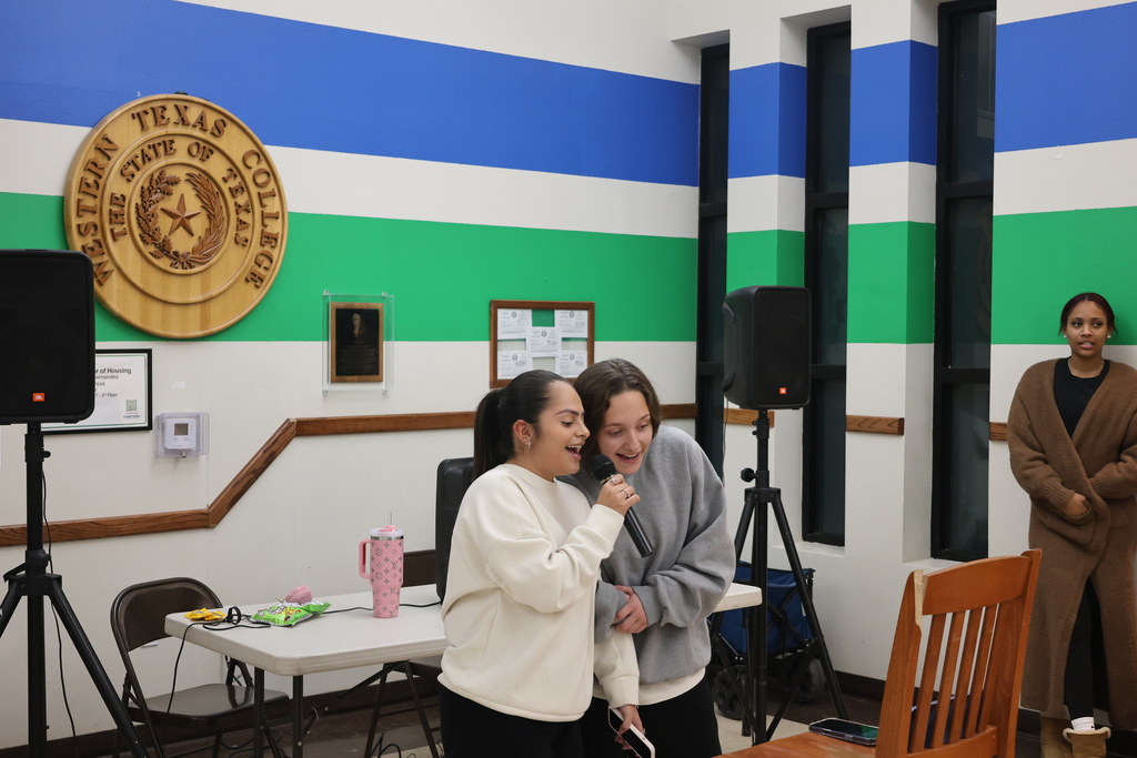 Two students sing karaoke while coach watches during open mic night at WTC.