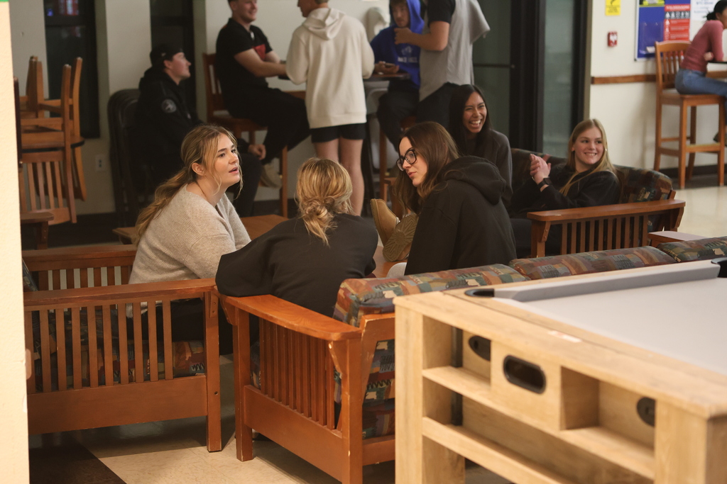 Students socialize and laugh while seated during open mic night in the WTC Student Commons.