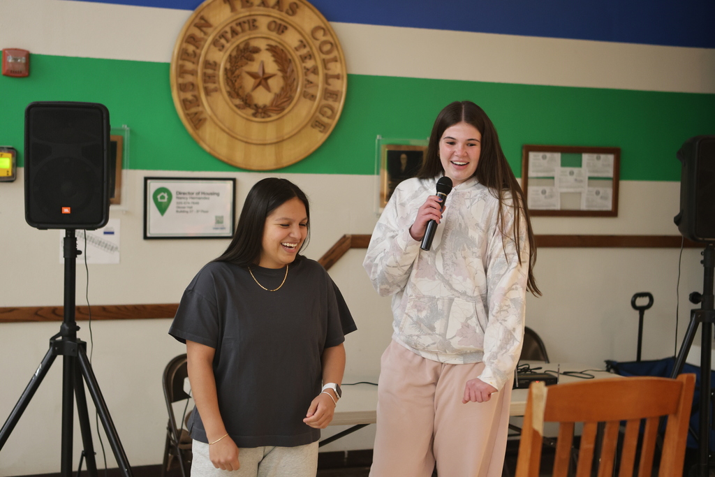 Students sing karaoke together in the WTC Student Commons with speakers and microphones.
