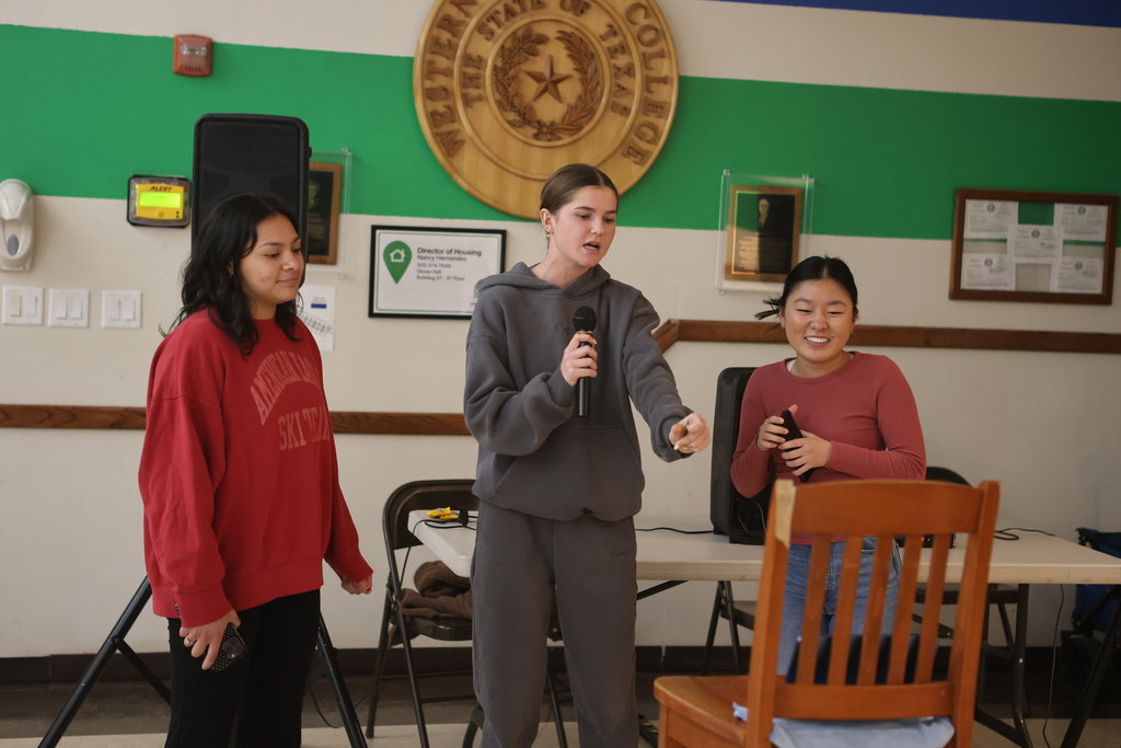 Students sing karaoke together in the WTC Student Commons with speakers and microphones.