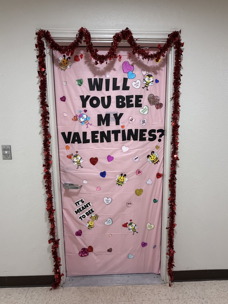 Pink Valentine’s door reads “Will You Bee My Valentines?” with hearts, bees, and red tinsel garland.