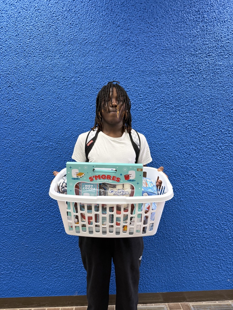 A man holds a laundry basket full of cocoa mix and snacks.
