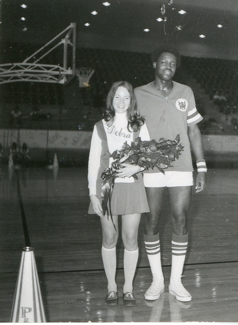 A man escorts a woman on a basketball court.