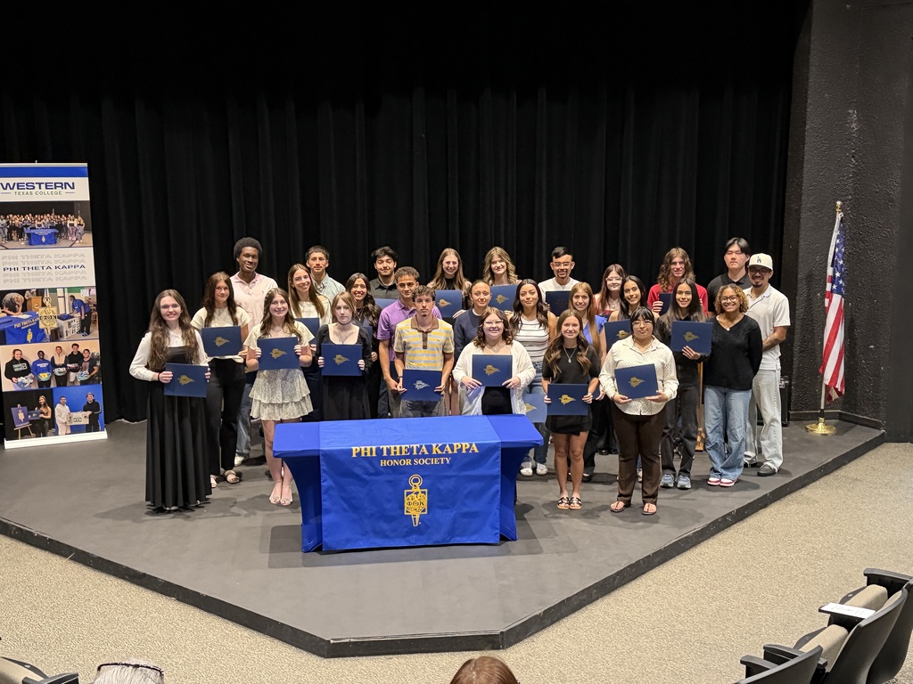 Group of students holding certificates on stage behind Phi Theta Kappa table during induction ceremony at Western Texas College.Group of students holding certificates on stage behind Phi Theta Kappa table during induction ceremony at Western Texas College.