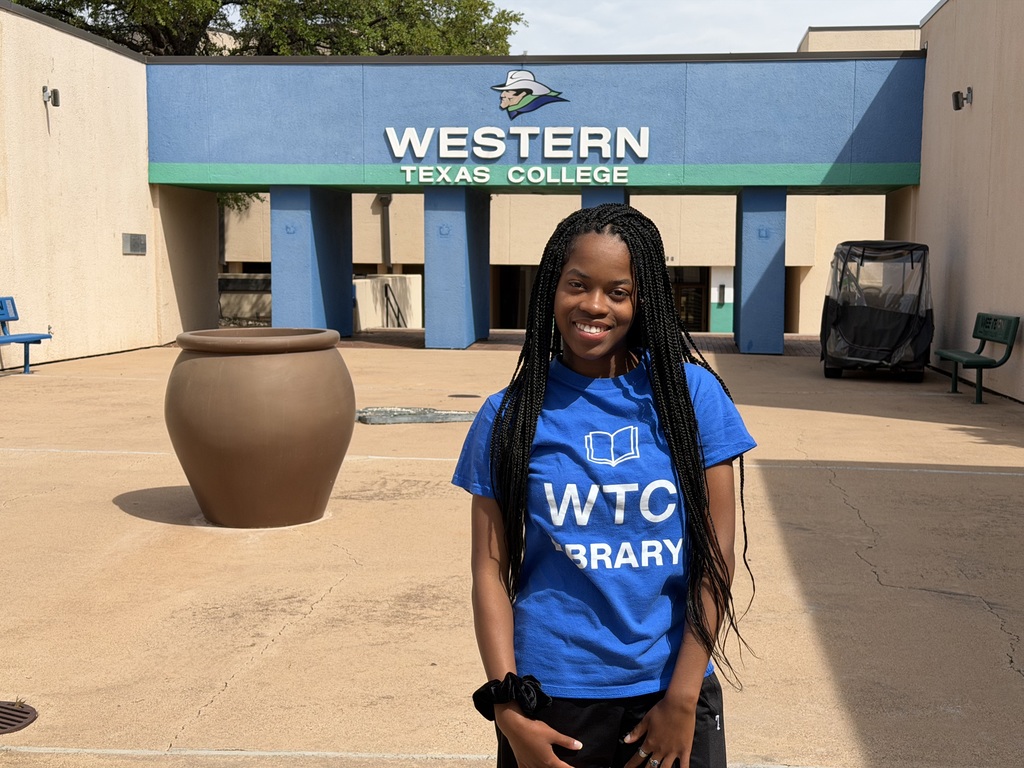 A woman wears a WTC Library shirt standing on the main walkway.