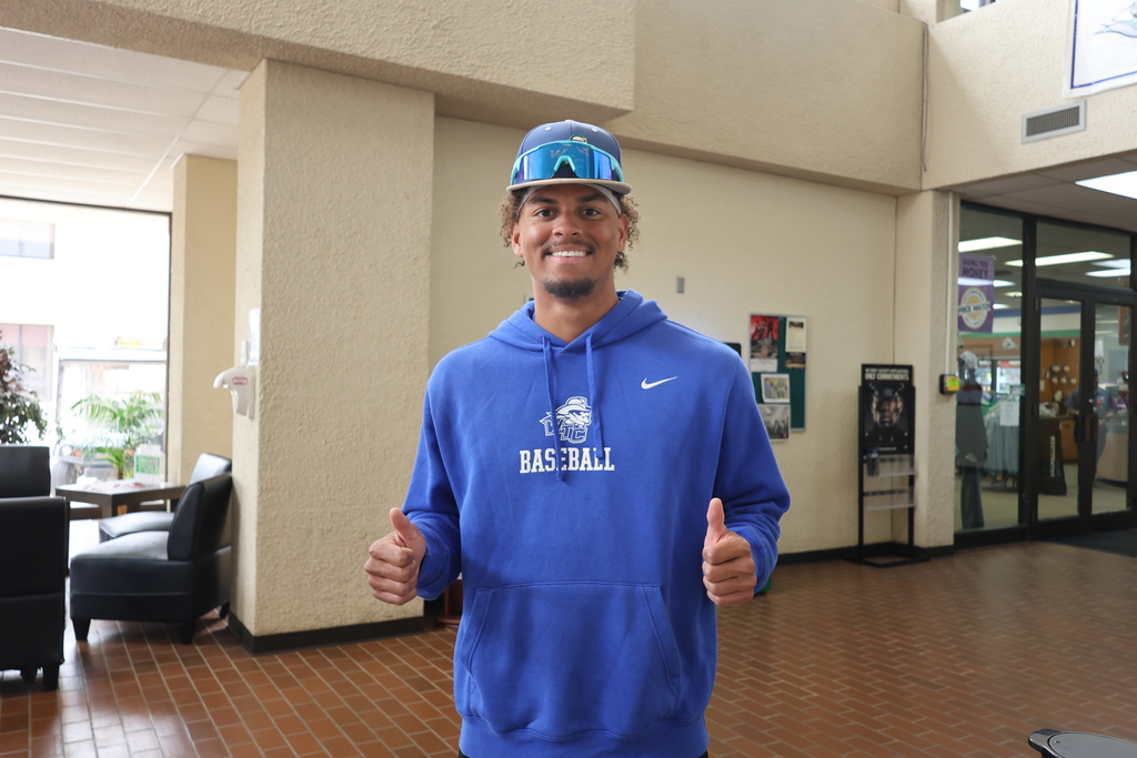 A man wearing a WTC baseball hoodie gives two thumbs up.