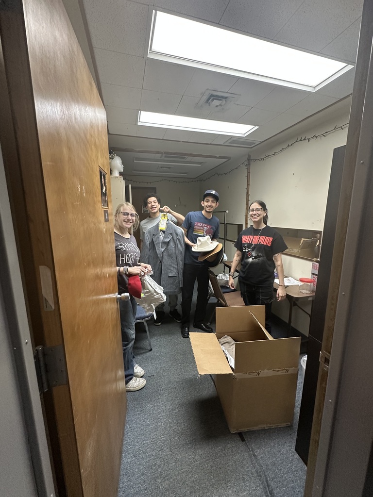 Four students pose with coats and hats during costume prep for All My Sons