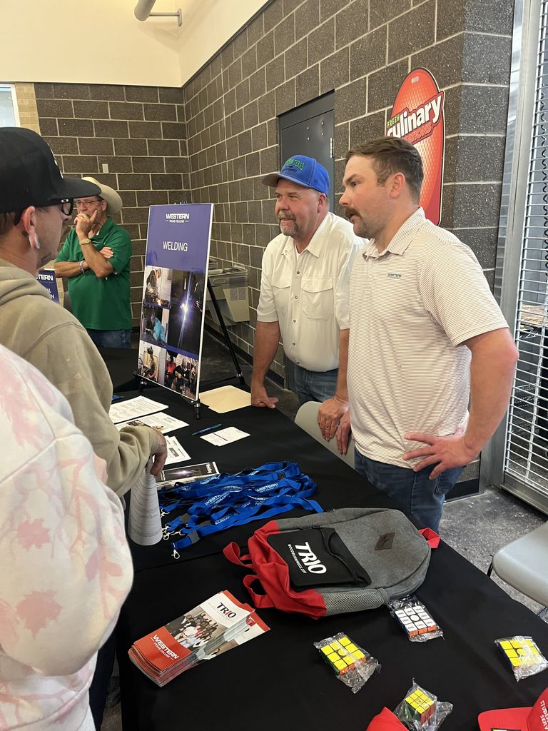 Staff speak with students at Western Texas College outreach table.