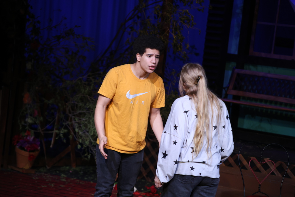 Two student actors perform emotional scene on stage set.