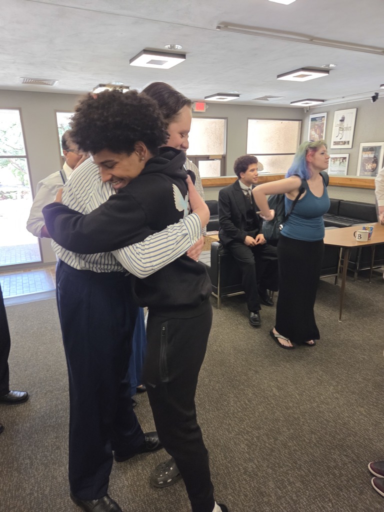 Student hugs guest in theater lobby after performance.