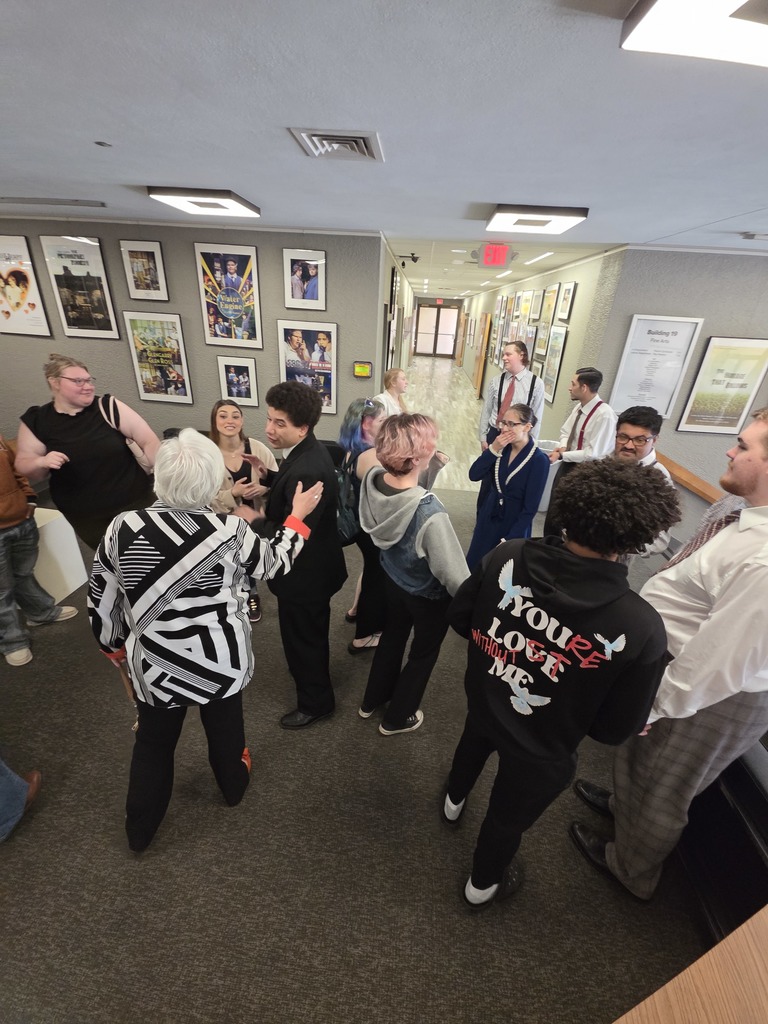Guests and student actors visit in theater lobby after performance.