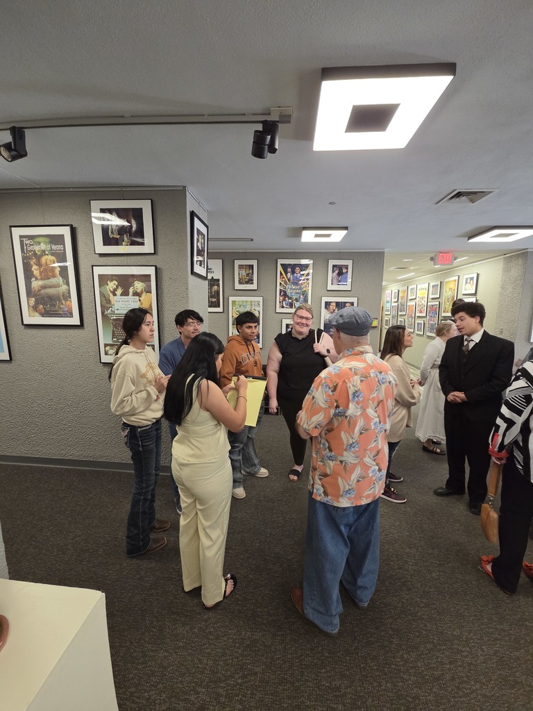 Audience members and student actors visit in theater lobby after show.