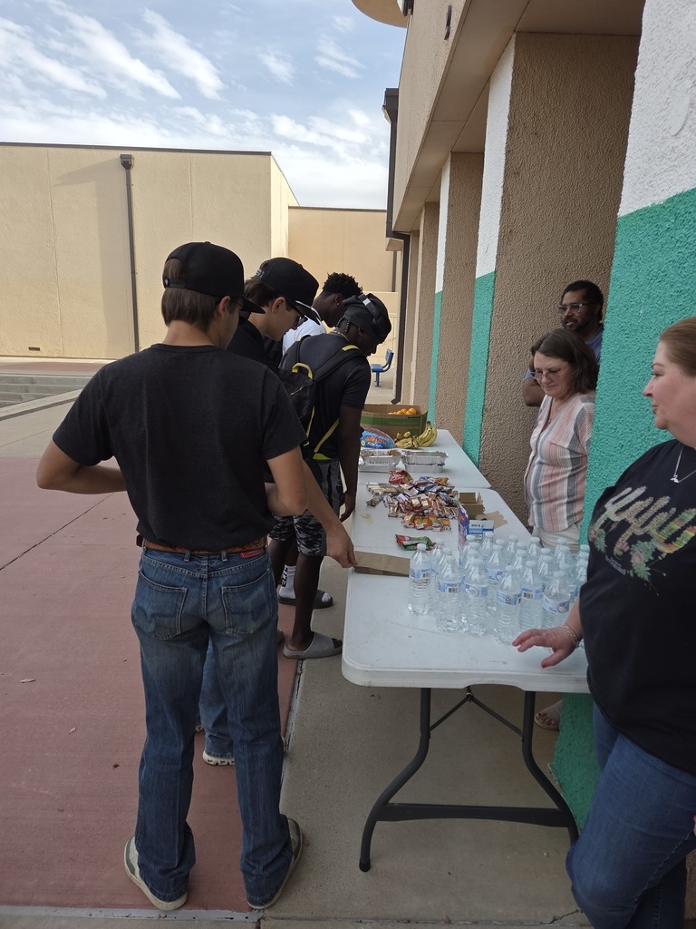Students gather at Fuel for Finals table receiving snacks and bottled water outside Library Building 2.