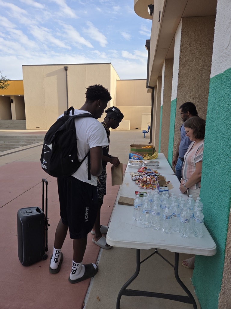 Students select snacks, fruit, and water at Fuel for Finals table outside campus library.
