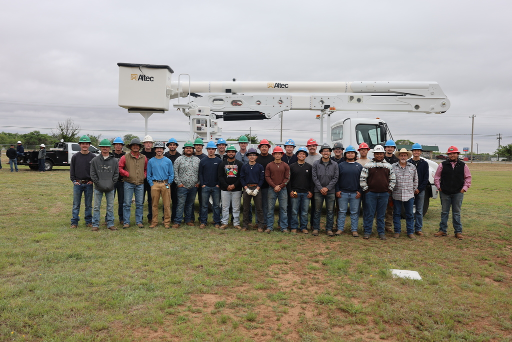 Group photo of lineworker students standing in front of bucket truck.