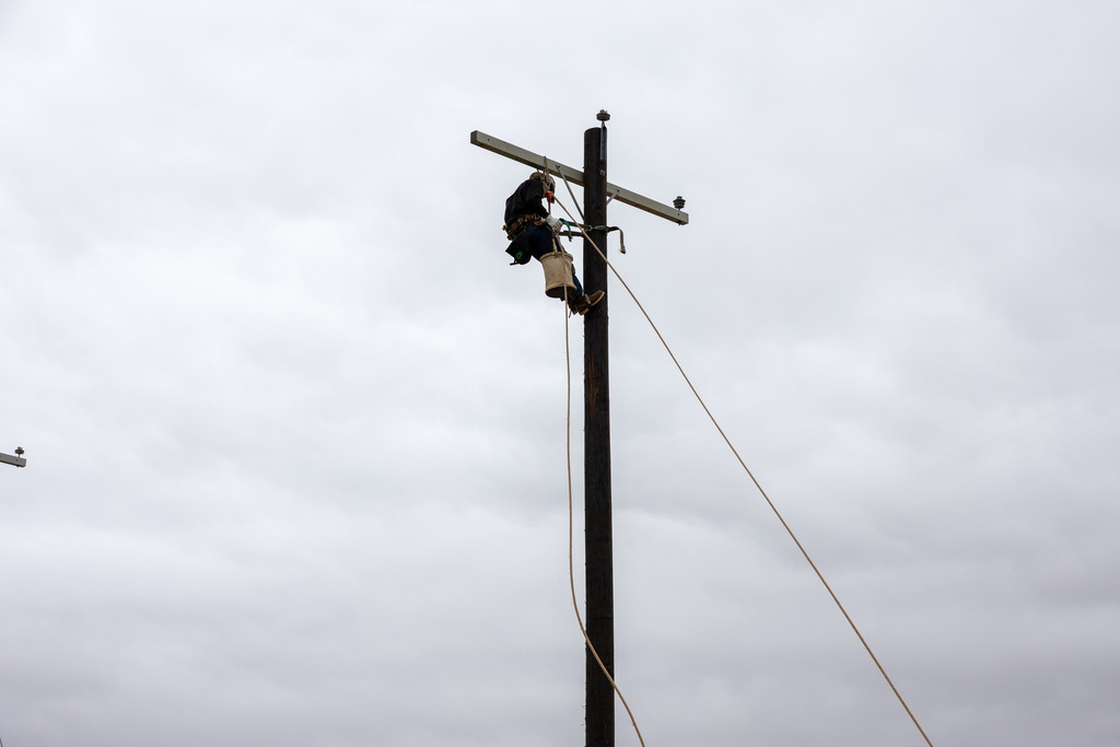 Student climbs utility pole during lineworker skills event.