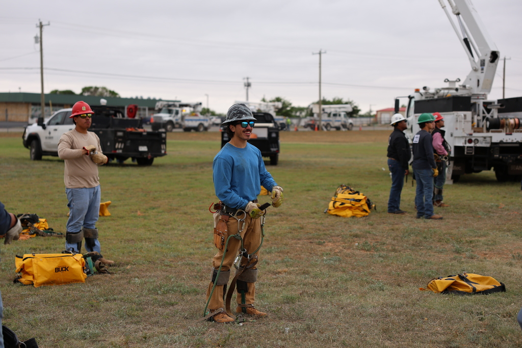 Lineworker student in safety gear smiles on field.