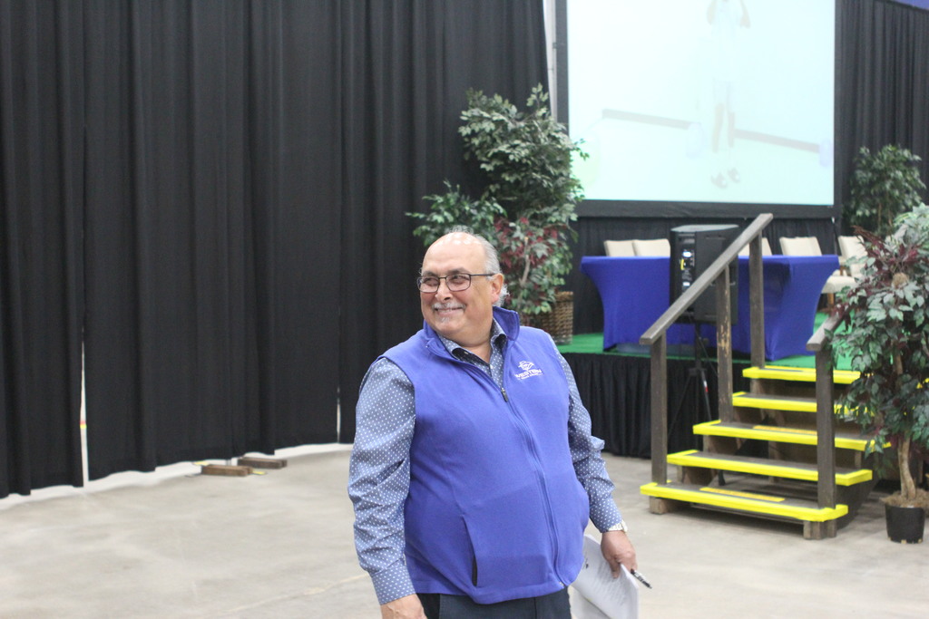 Standing in front of the stage, Mr. Ramon smiles at someone off camera during last year's commencement rehearsal.
