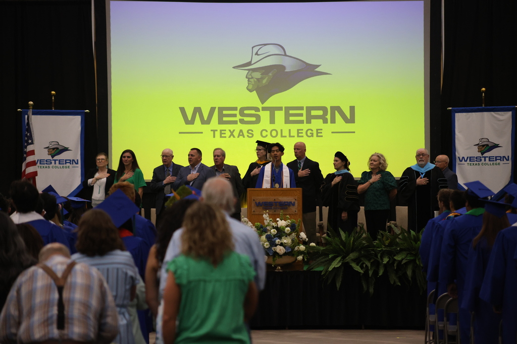 College officials and graduate stand on stage during ceremony with Western Texas College logo displayed behind them.