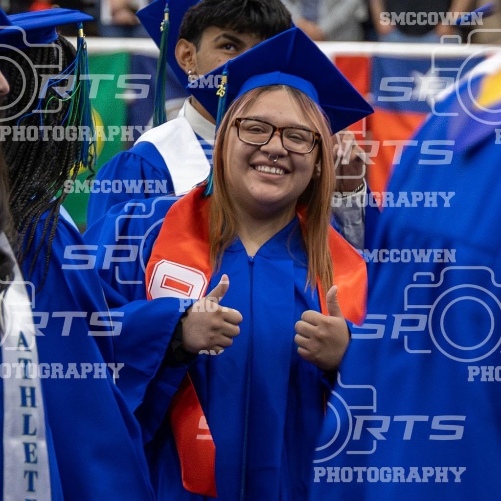Graduate smiles with two thumbs up.