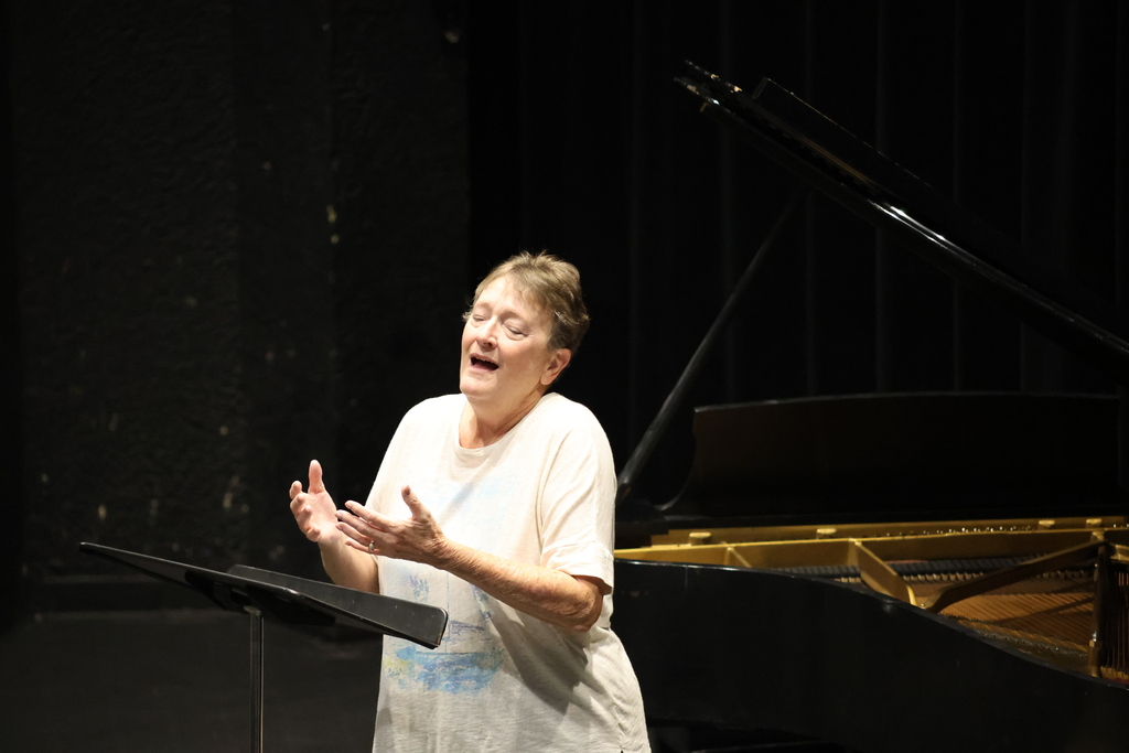 Dr. Alesio rehearses in front of a grand piano on stage.